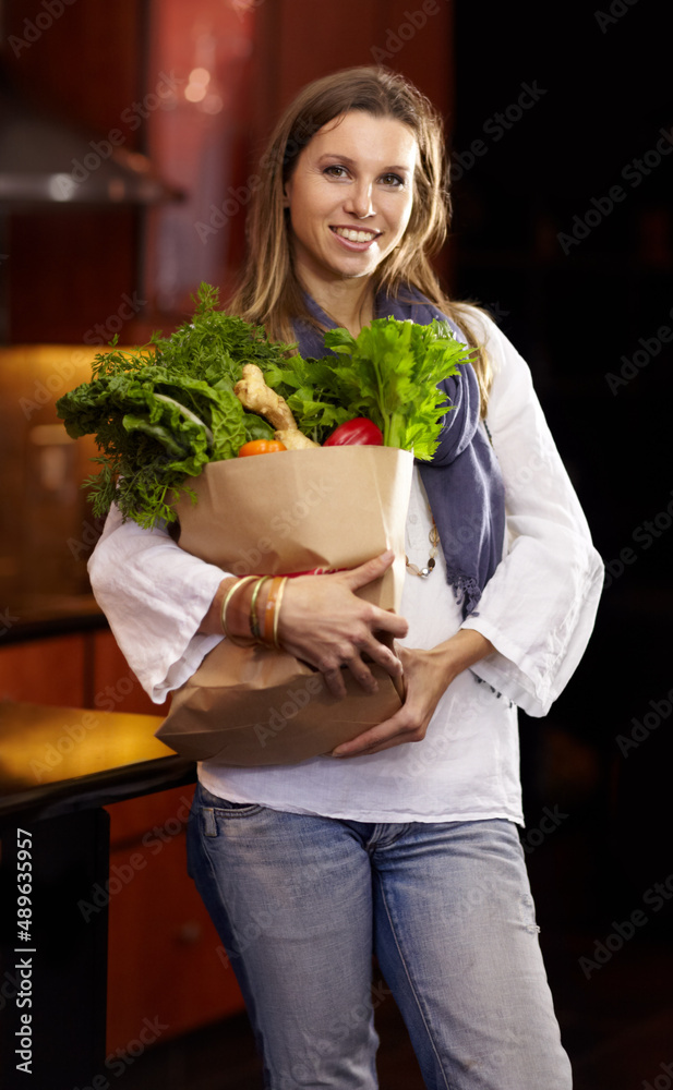 Shes proud of her healthy food choices. Attractive woman holding a paper bag of fresh vegetables.