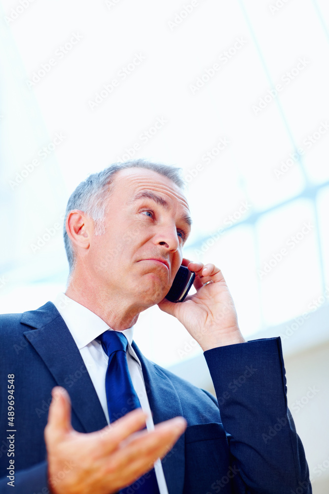 Executive looking uncertain while on phone. Senior executive with puzzled look while on cell phone.