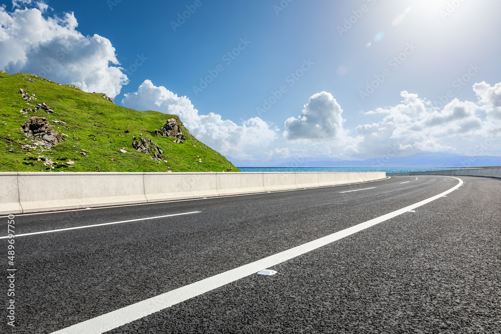 Asphalt road and mountain with sea natural scenery under blue sky