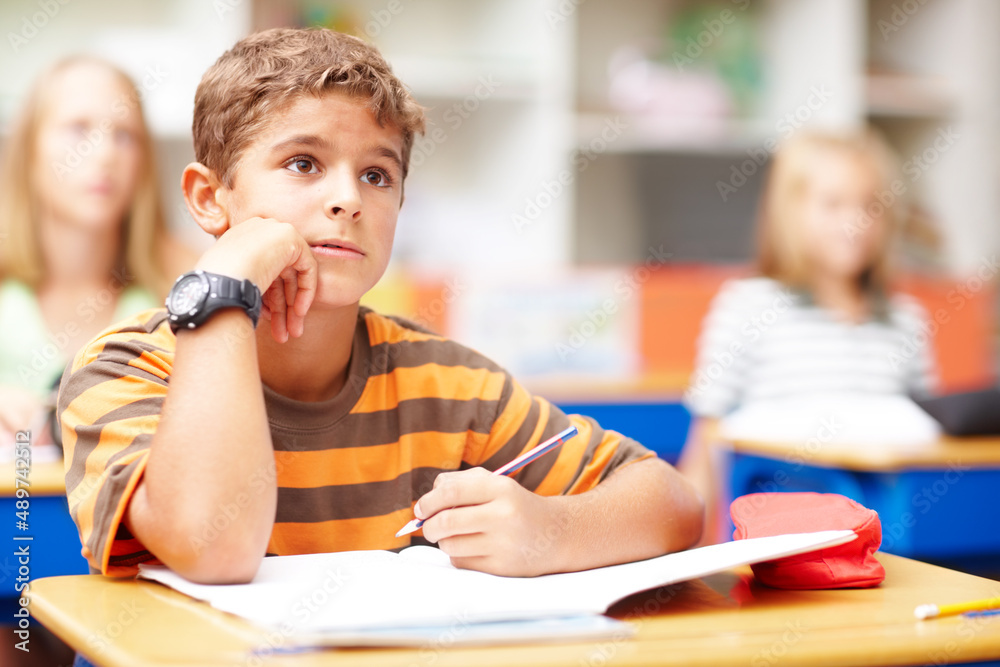 Inspired children become first-class achievers. Young boy in class listening to his teacher while ta