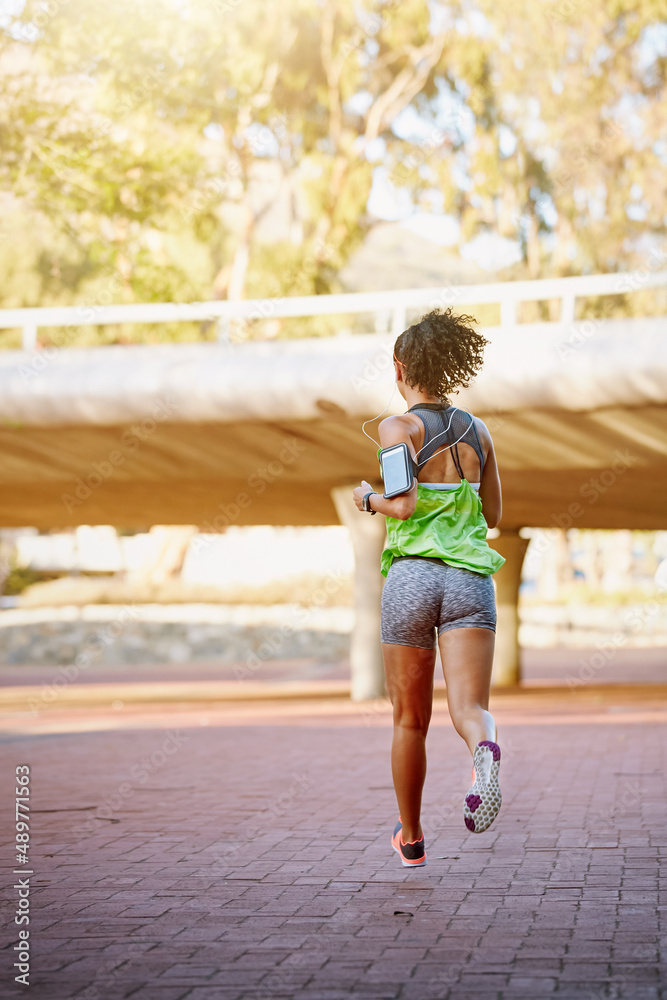 Out on her daily jog. Rear view shot of a sporty young woman out for a run.