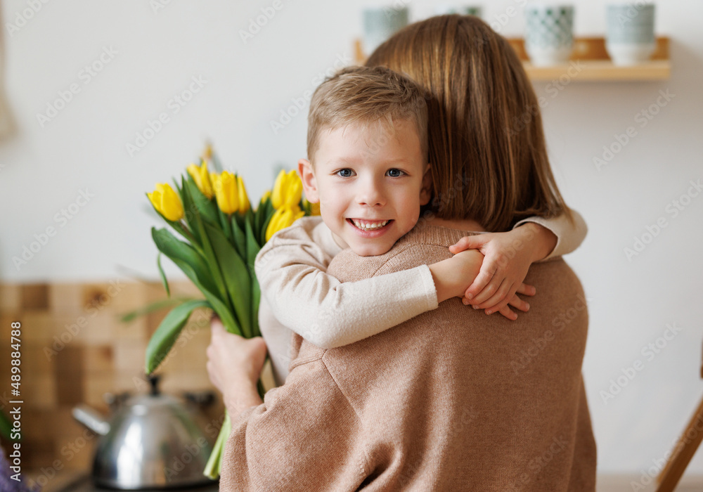 Cheerful boy with bouquet congratulations mother