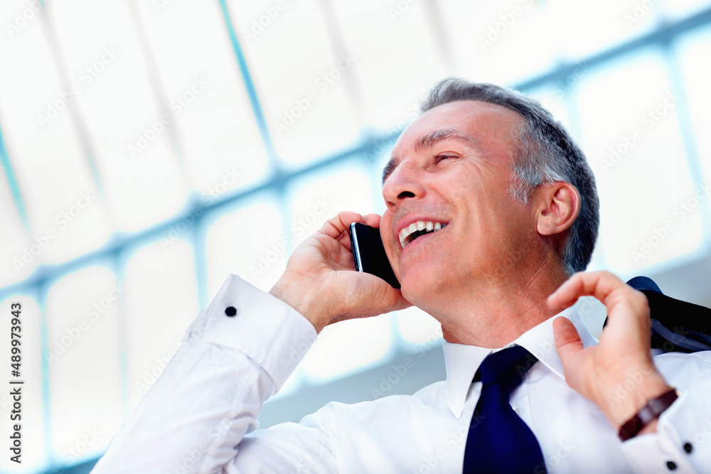 Businessman having discussion on cell phone. Executive smiling and looking into distance while talki