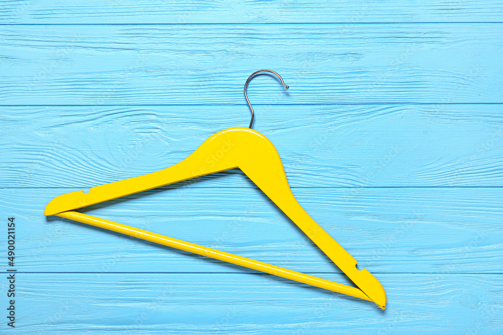 Clothes hanger on color wooden background