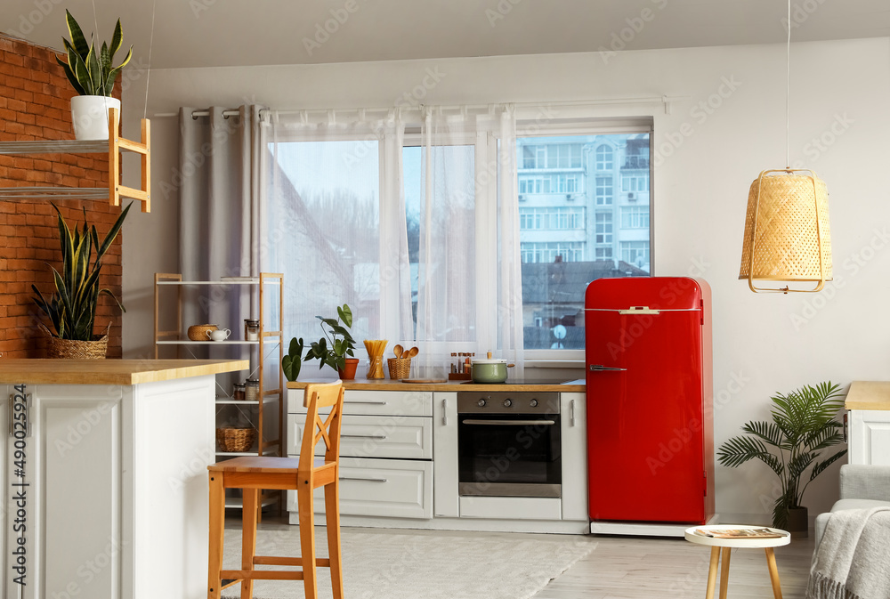 Interior of modern kitchen with red fridge and oven