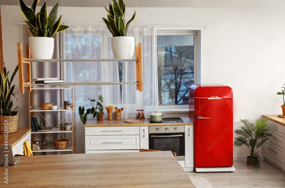 Interior of modern kitchen with red fridge and shelving unit