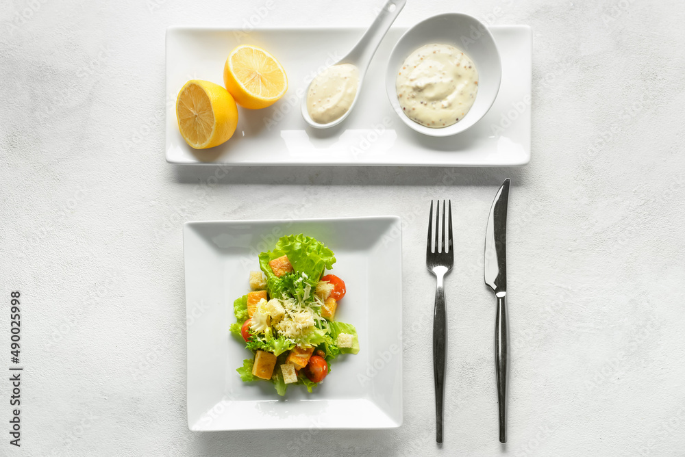 Plate of tasty vegan Caesar salad and sauce on white background