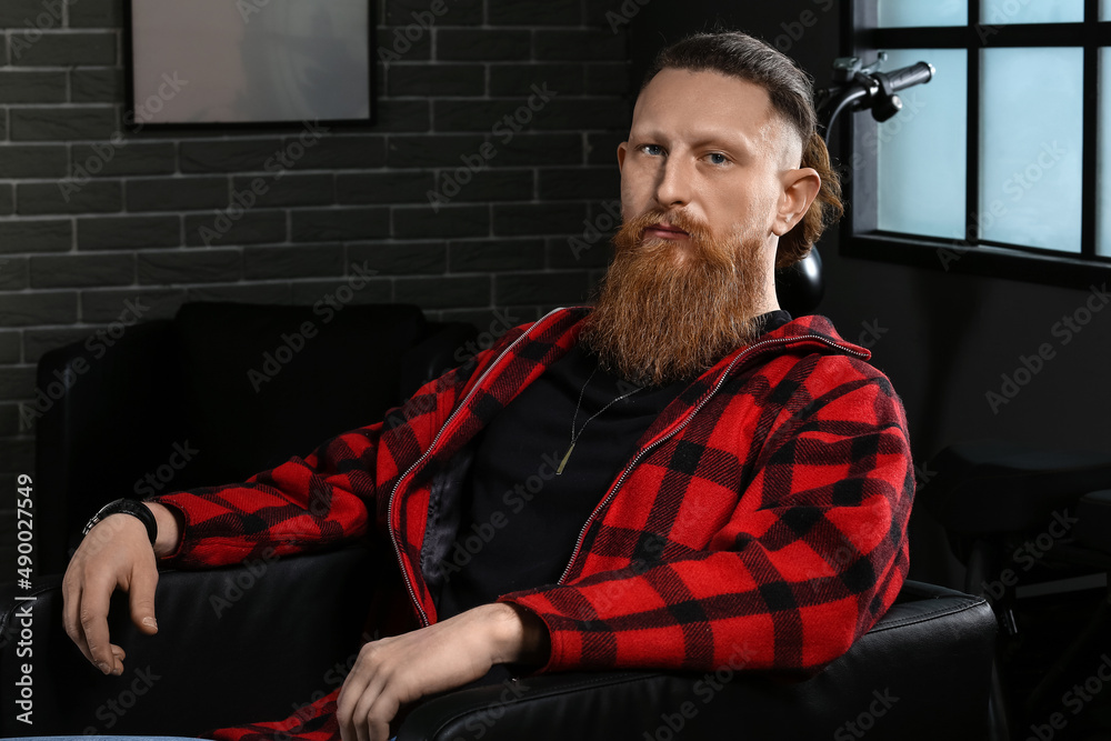 Portrait of handsome bearded man sitting in armchair at home