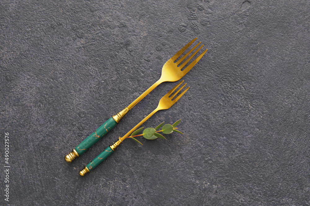 Stylish stainless steel forks on black background