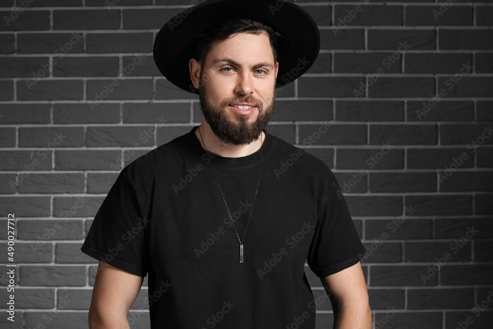 Stylish bearded man on dark brick background