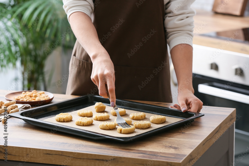 Woman preparing peanut cookies at kitchen table, closeup