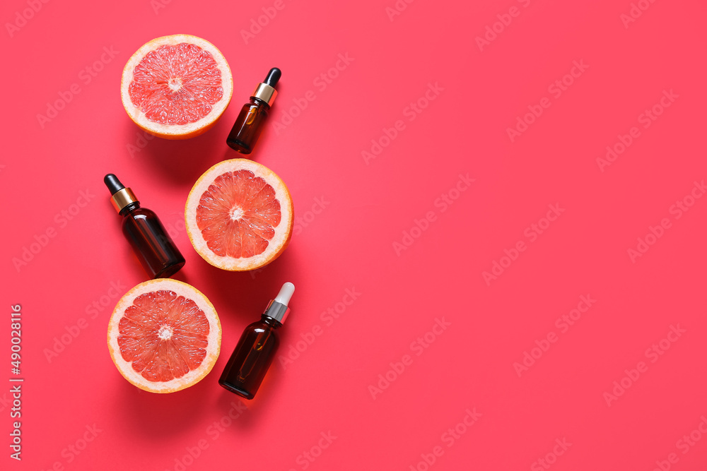 Composition with bottles of essential oil and ripe grapefruits on color background