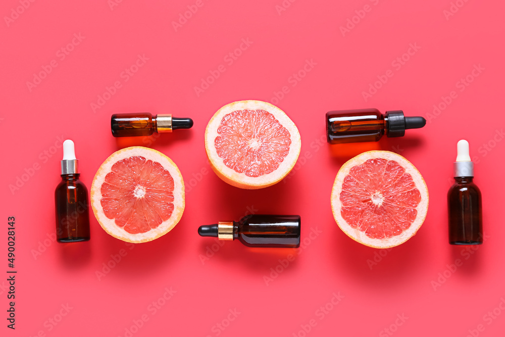 Composition with bottles of essential oil and juicy grapefruits on color background