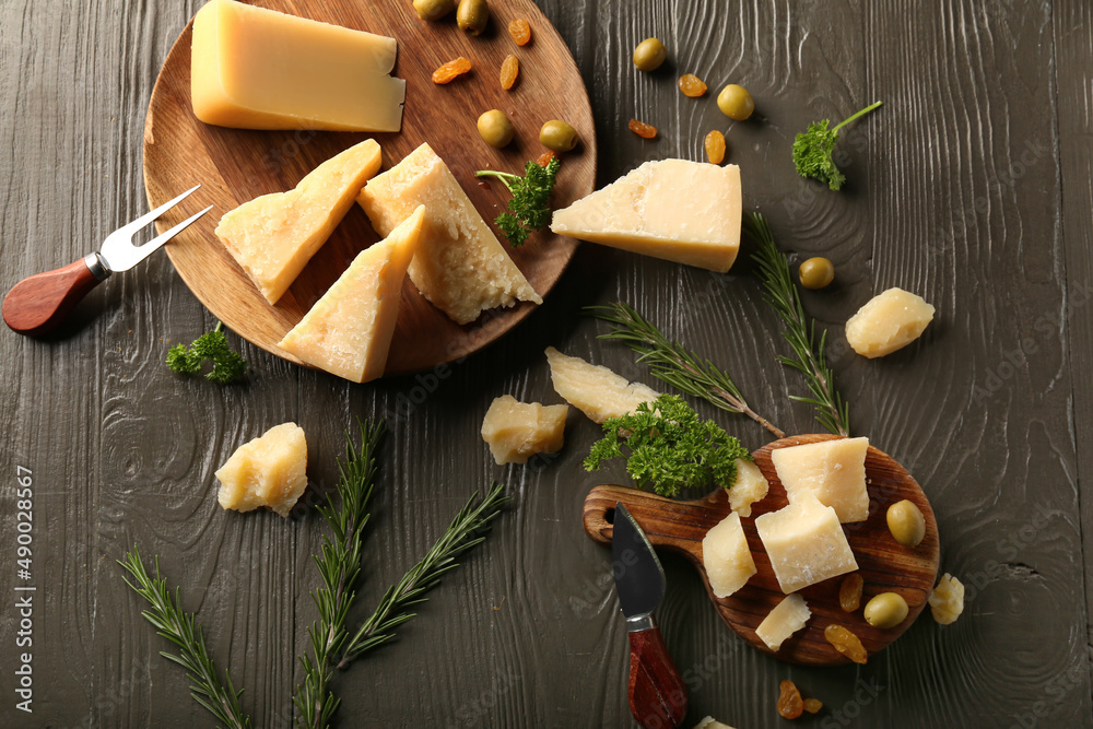 Plate and board with pieces of tasty Parmesan cheese on brown wooden background