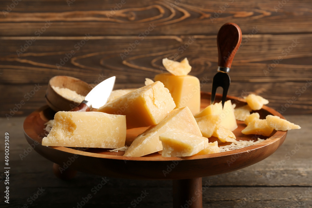 Stand with pieces of tasty Parmesan cheese on wooden background