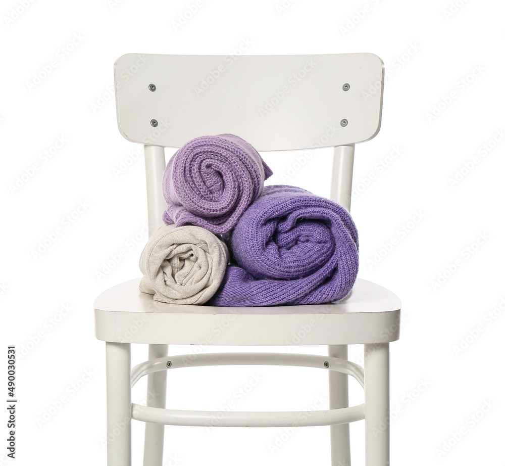 Rolled sweaters on chair against white background