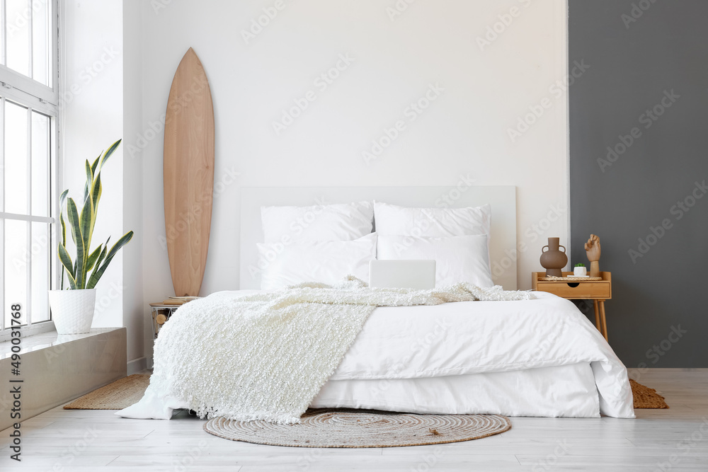 Interior of modern bedroom with wooden surfboard and table