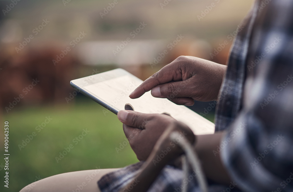 The modern way to manage a farm. Shot of an unrecognisable man using a digital tablet while working 