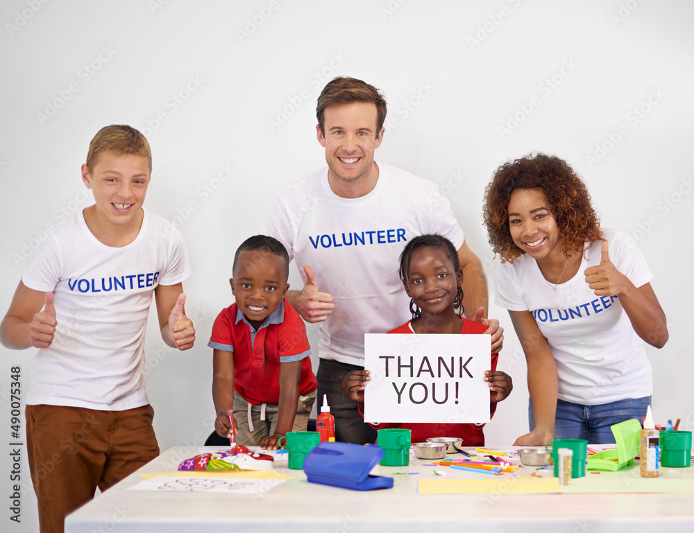 Every child needs someone to look up to. Portrait of a volunteer holding up a thank you sign while w