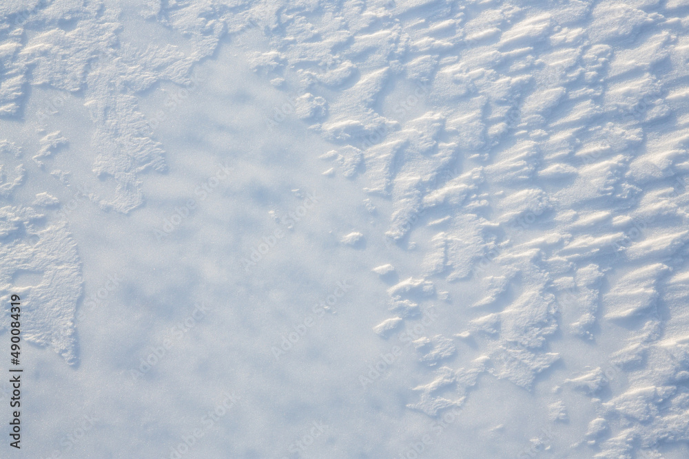 Beautiful winter background with snowy ground. Natural snow texture. Wind sculpted patterns on snow 