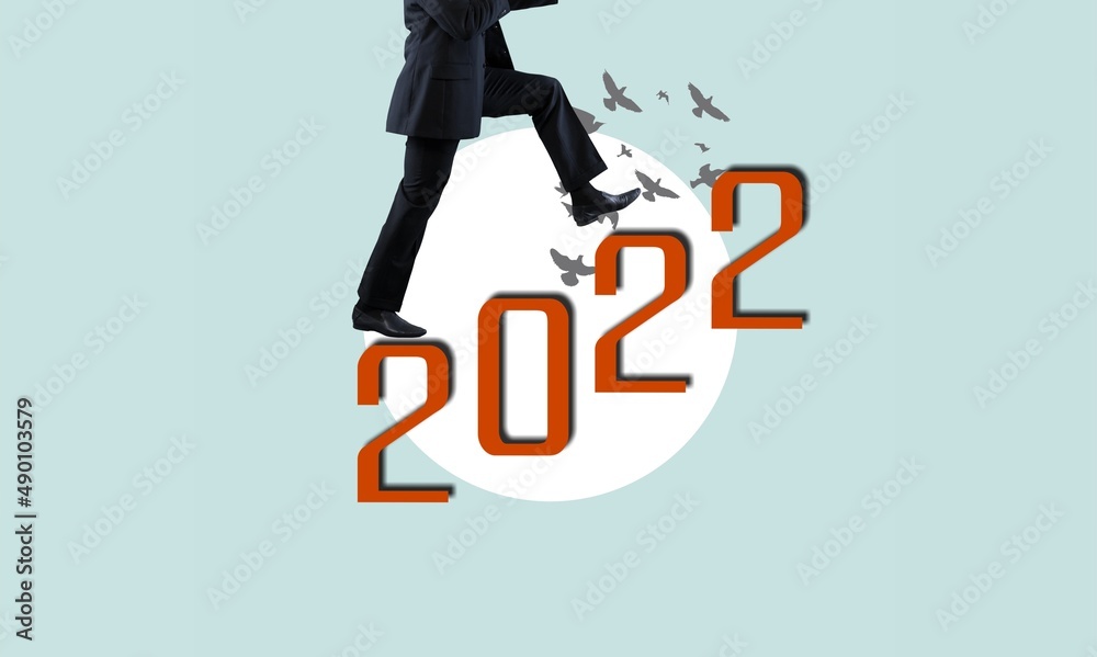 一个男人像爬楼梯一样爬上2022年的文字。2022年的新挑战和成功。艺术拼贴。