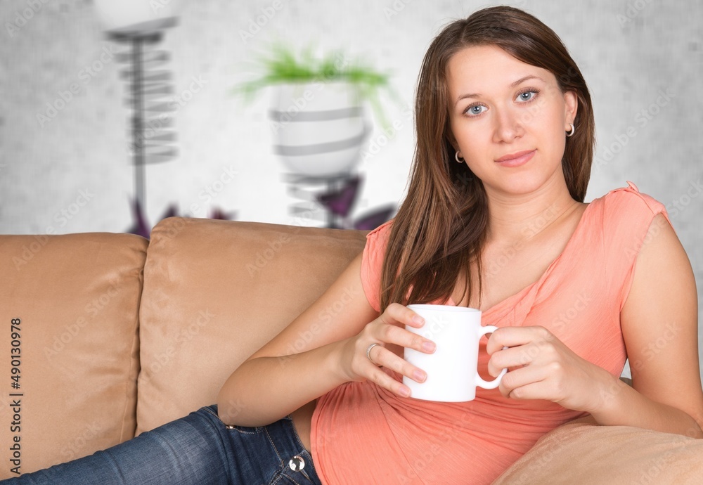 Woman hands holding cup of tea or coffee. Relax at home on sofa.