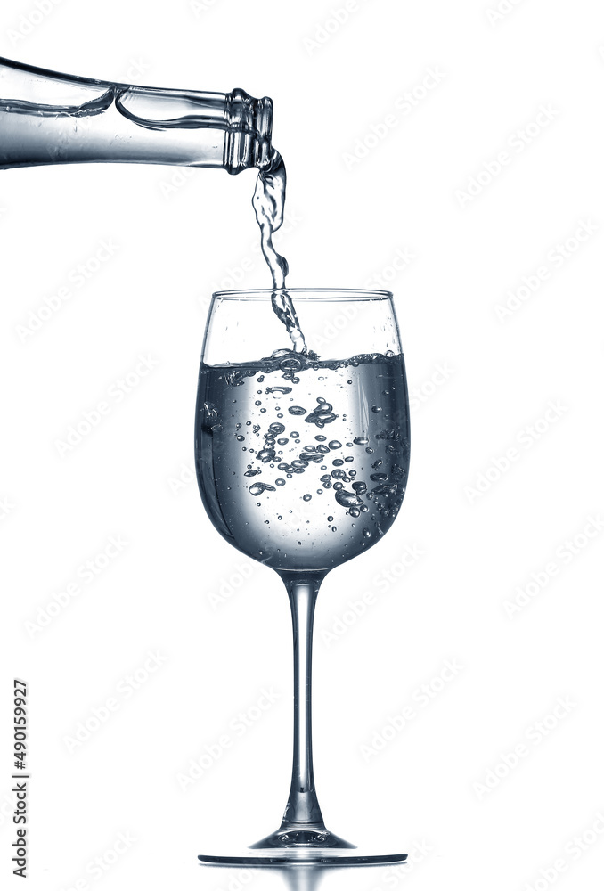 Pouring of clear water in glass isolated on white