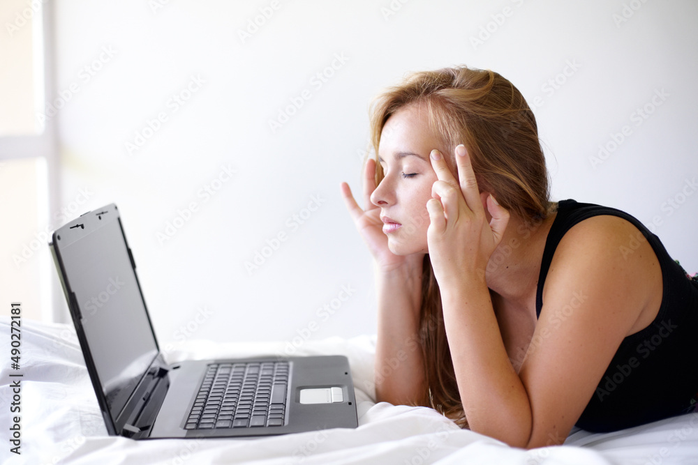 Getting some online advice for migraines. Shot of a beautiful young woman looking frustrated while u