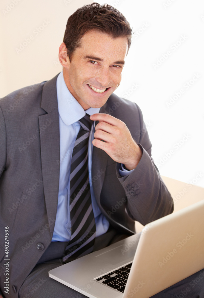 Hes a savvy businessman. Portrait of a handsome young businessman using his laptop.