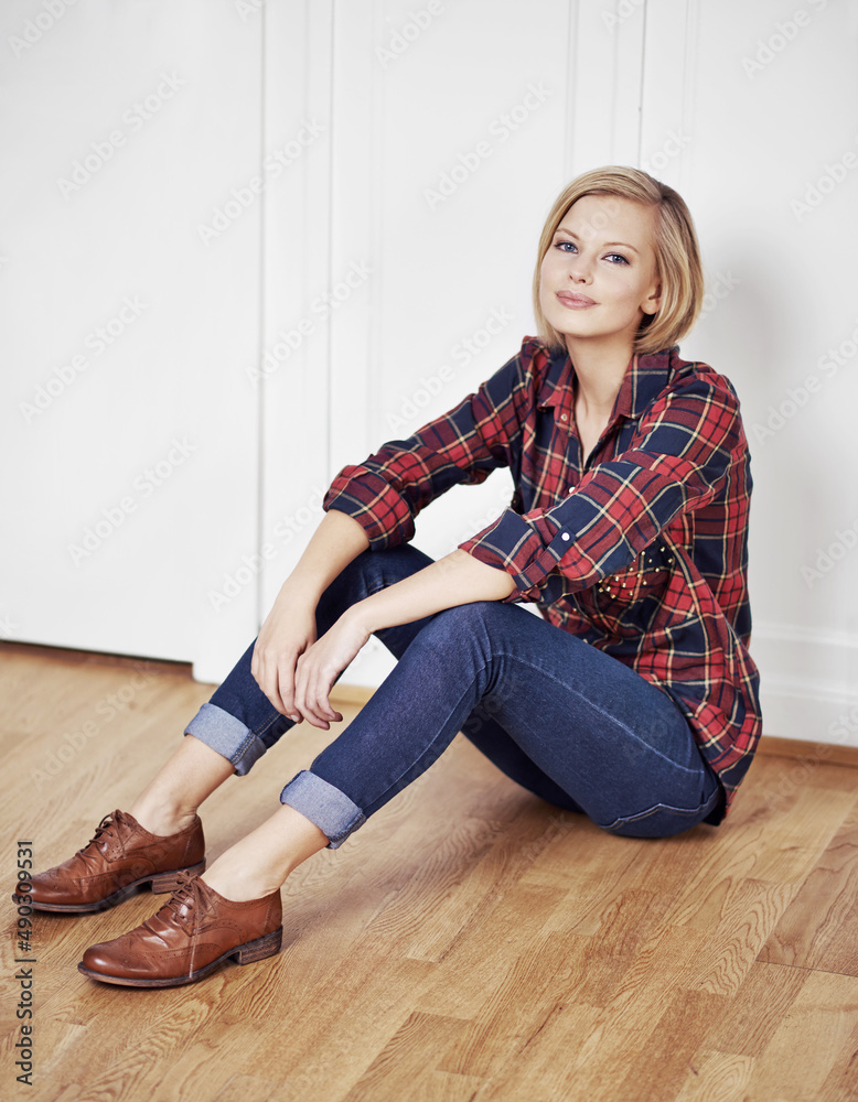 Comfortable style. A portrait of a beautiful young woman sitting on a wooden floor at home.