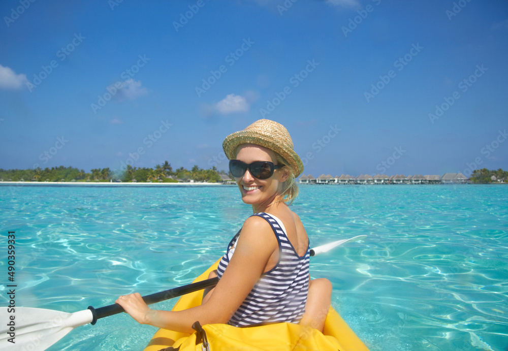 向海滩划水。一位美丽的年轻女子在热带海洋中的船上划水。