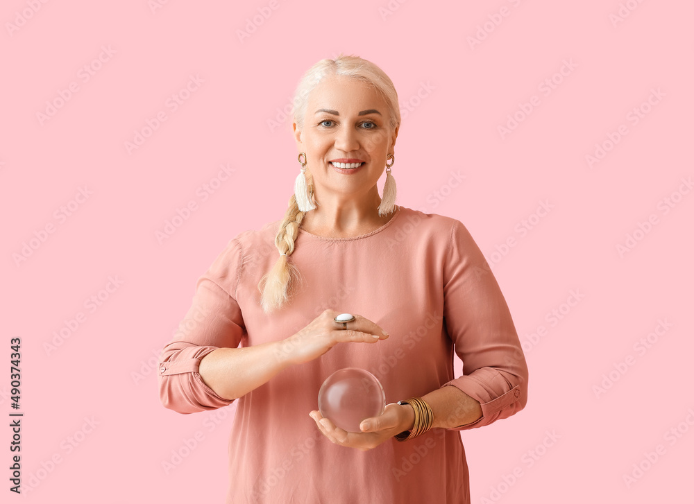 Mature woman with crystal ball on color background