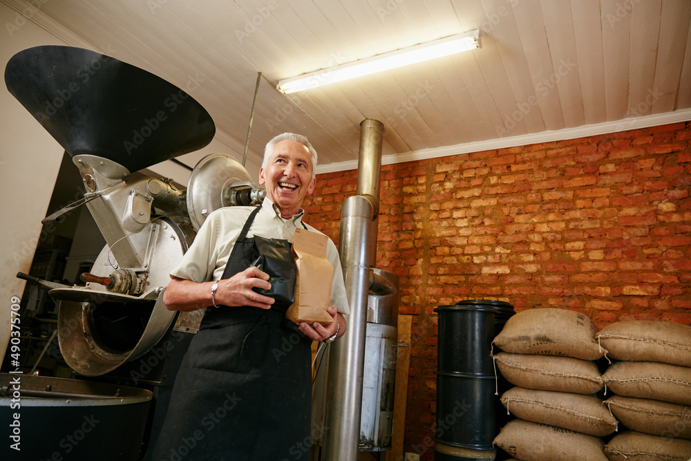 We brew a variety of flavours. Low angle portrait of a senior man holding bags of coffee beans while