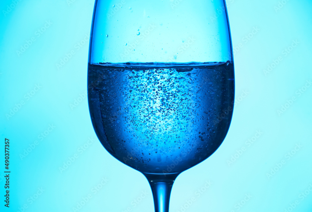 Glass of clear water on blue background