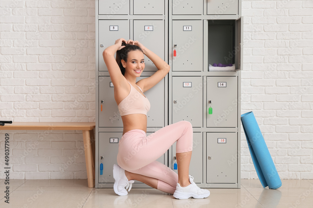 Sporty young woman near locker in change-room