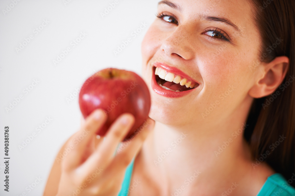 They say apples keep the doctor away. Portrait of a beautiful young woman eating an apple.