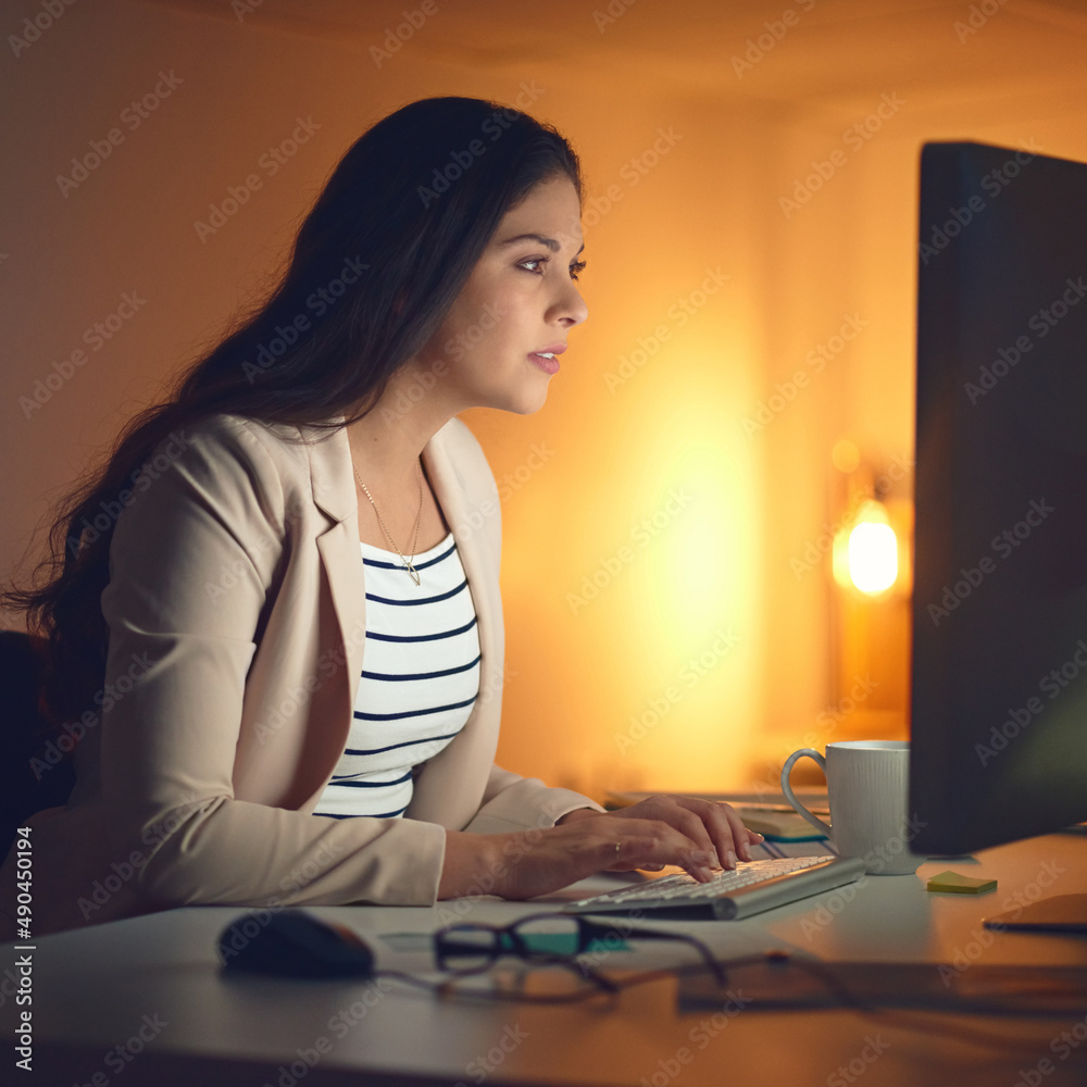 Stopping at nothing to get it done. Shot of a young businesswoman using a computer during a late nig