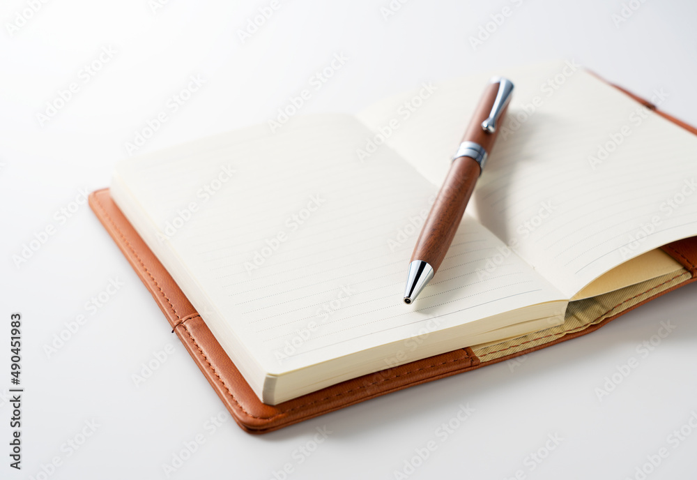 A leather notebook and pen set against a white background.