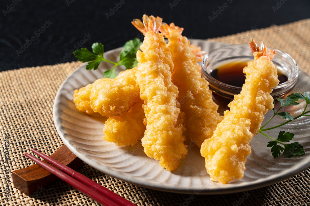 Shrimp tempura on a plate placed against a black background.