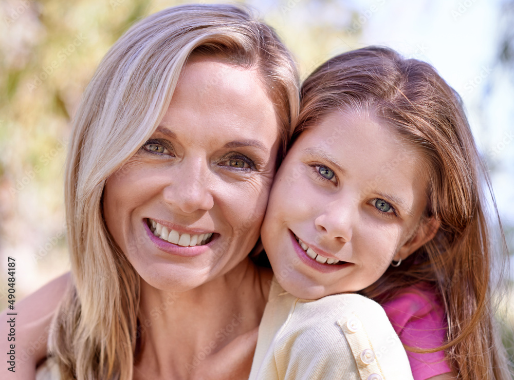 Shes my angel. A smiling mother with her daughter on her back while outdoors.