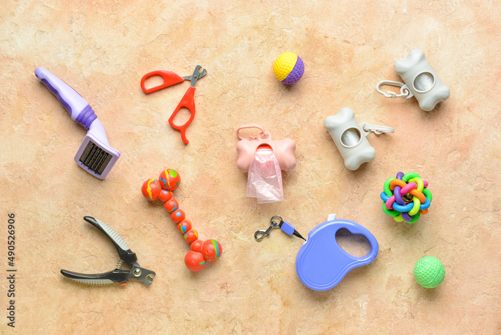 Different pet care accessories and dispensers with pet waste bags on color background