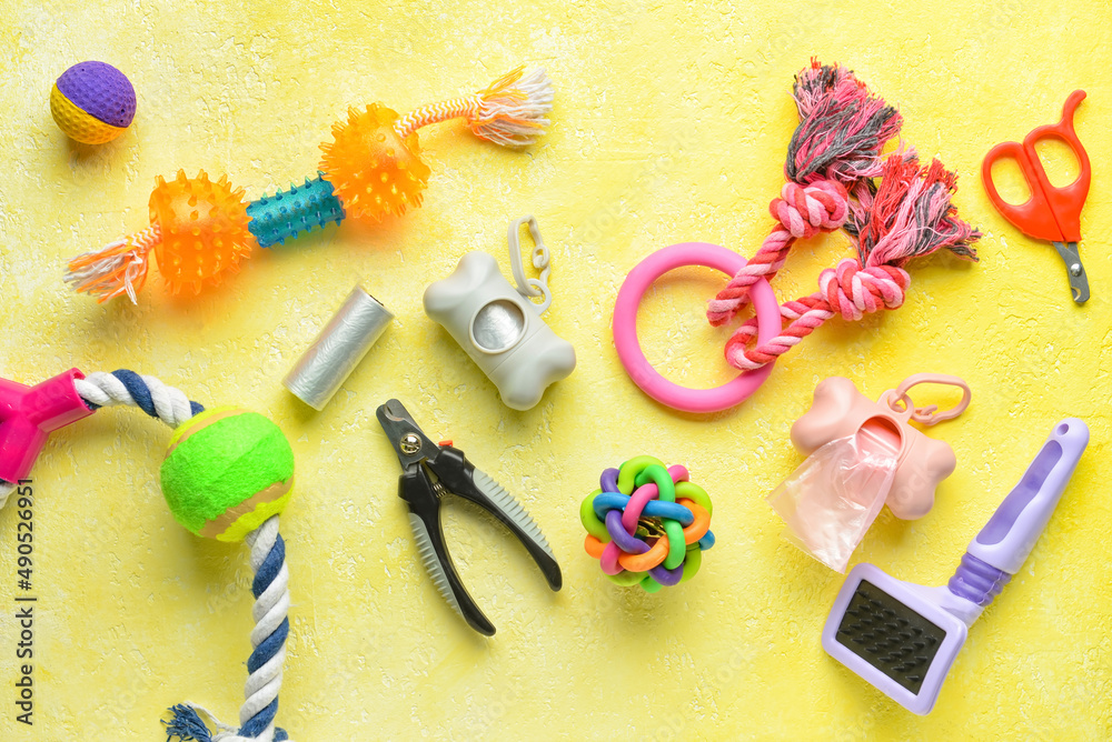 Different pet care accessories and waste bags on yellow background