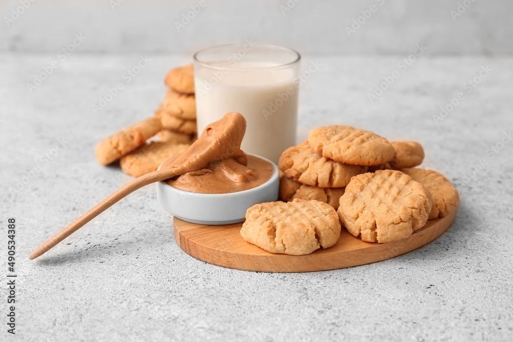 Wooden board with tasty peanut cookies on light background