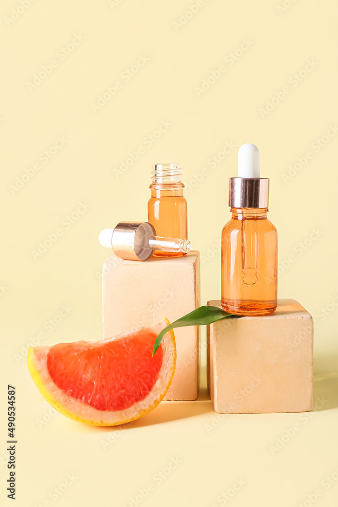 Composition with bottles of essential oil, grapefruit slice and decor on color background