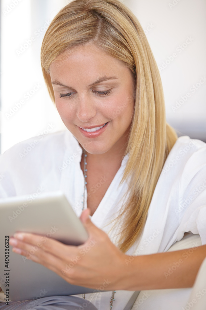 Checking her work schedule. A beautiful young blonde woman working on her digital touchpad.