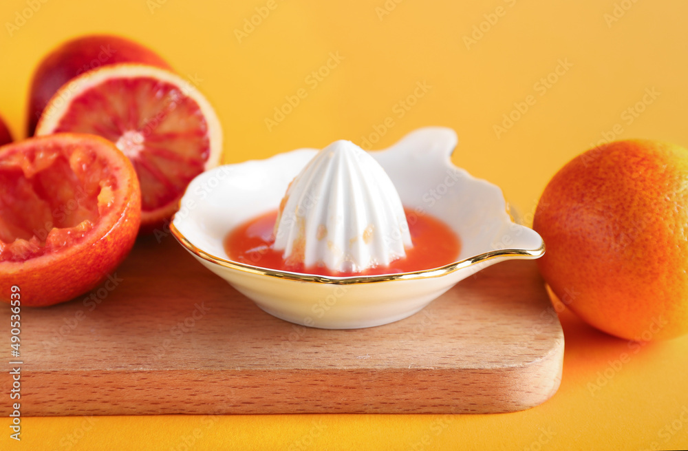 Ceramic juicer and grapefruits on orange background