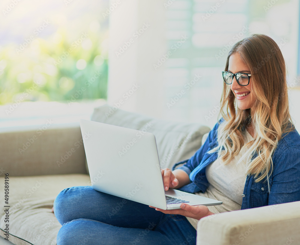 Shes happy with her new wifi. Shot of an attractive young woman using her laptop while sitting on th