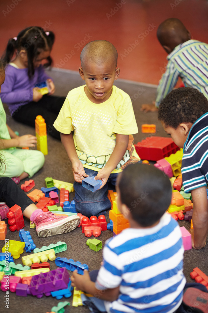 Sharing is caring. Play time for a group of young children who are playing with plastic blocks.