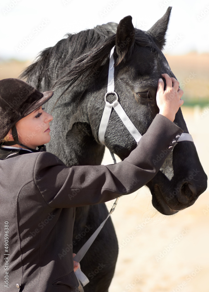 Getting ready for a long ride. Shot of a young female rider stroking her horses face.