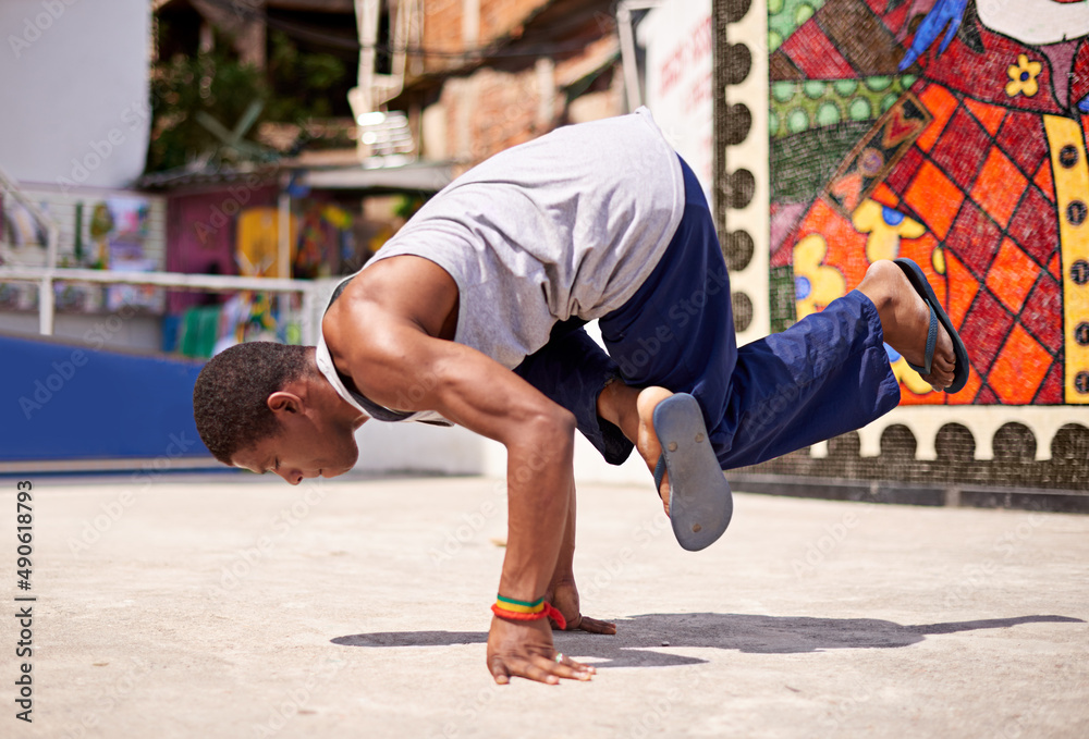 Capoeira culture. Low angle shot of a young male breakdancer in an urban setting.